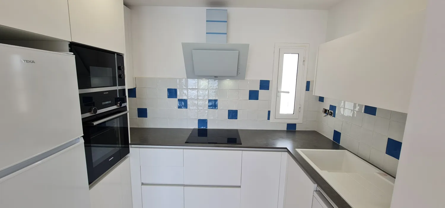 Cocina reformada con detalles en azul y campana de diseño
