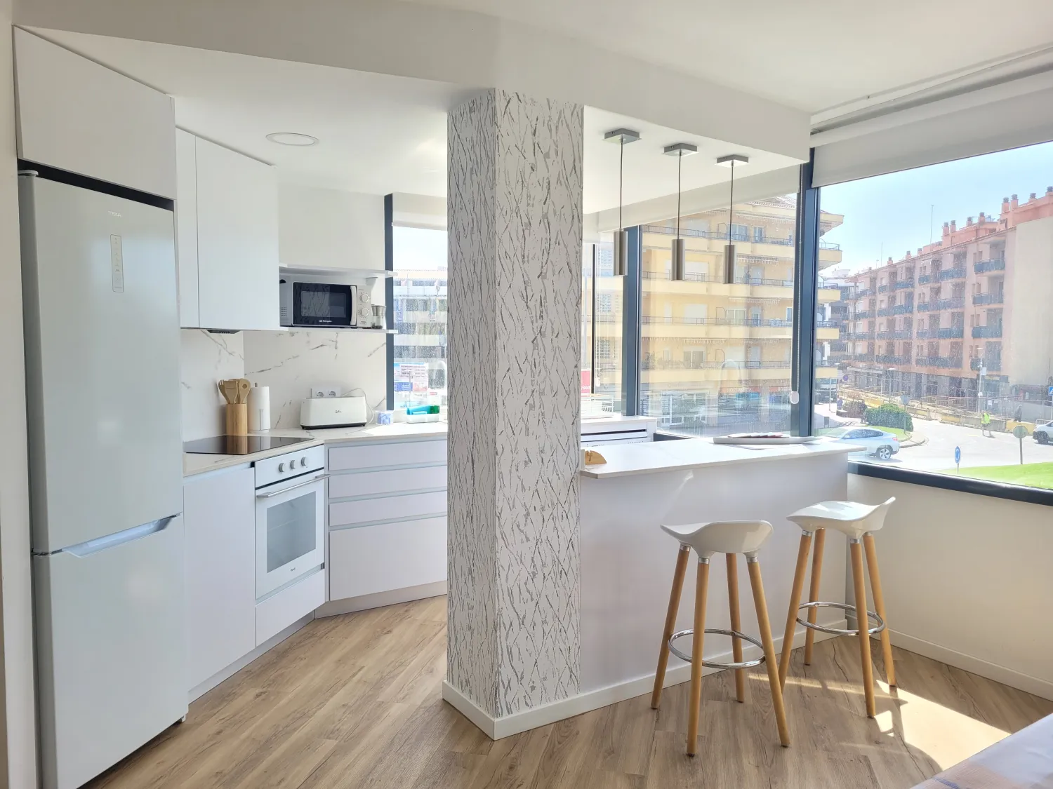 Cocina abierta al salón con barra y taburetes