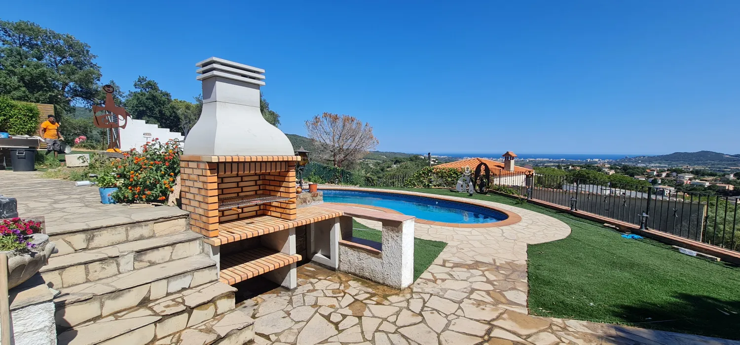 Terraza con barbacoa de obra y piscina con vistas al mar